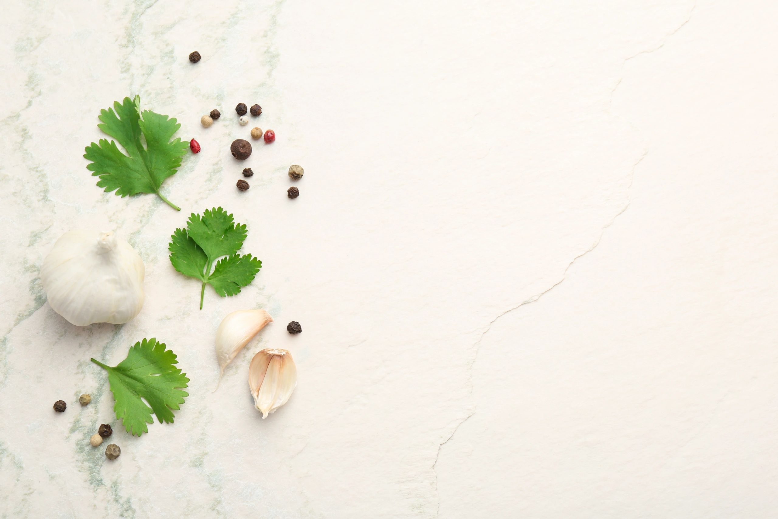 Fresh coriander leaves, garlic and peppercorns on light textured table, flat lay